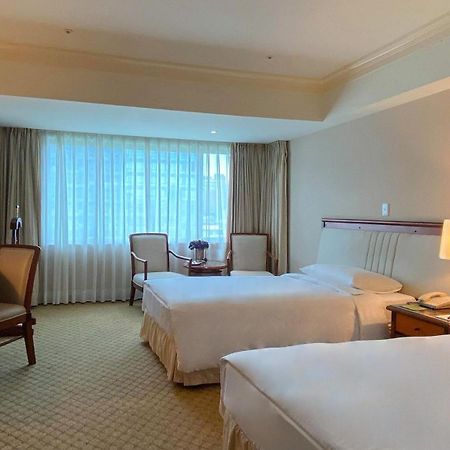 Evergreen Laurel Hotel - טאיצ'ונג מראה חיצוני תמונה The photo shows a hotel room featuring two single beds positioned near each other. There's a light-colored carpet on the floor and a large window with sheer curtains that allows natural light to fill the space. In the room, there are two chairs place