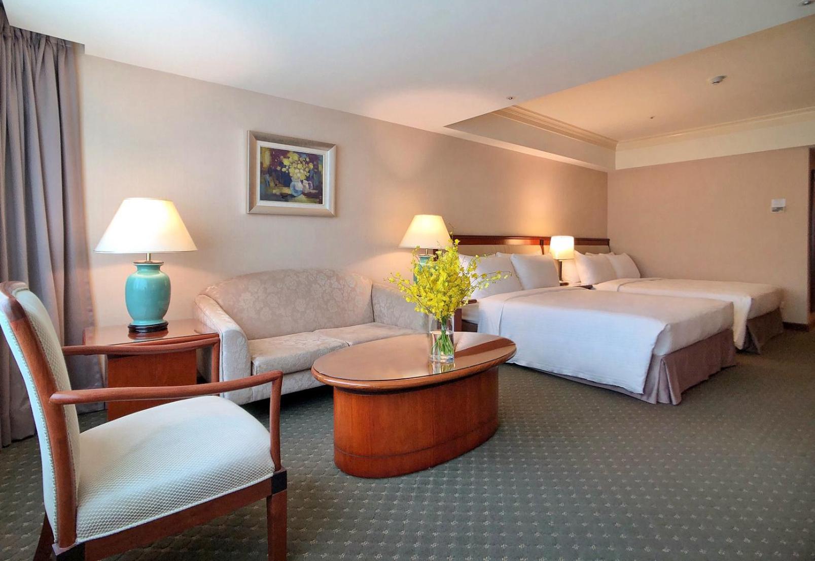 Evergreen Laurel Hotel - טאיצ'ונג מראה חיצוני תמונה The photo shows a hotel room featuring two beds, a small seating area, and a coffee table. The walls are painted in soft, neutral colors, and there is a framed piece of artwork hanging on the wall. A potted plant with yellow flowers is placed on the 