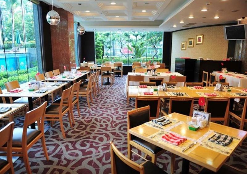 Evergreen Laurel Hotel - טאיצ'ונג מראה חיצוני תמונה The photo shows an interior of a restaurant with a spacious layout. There are several wooden tables, each set with napkins and utensils. The floor has a decorative carpet, and large windows provide a view of greenery outside. The lighting is bright, 
