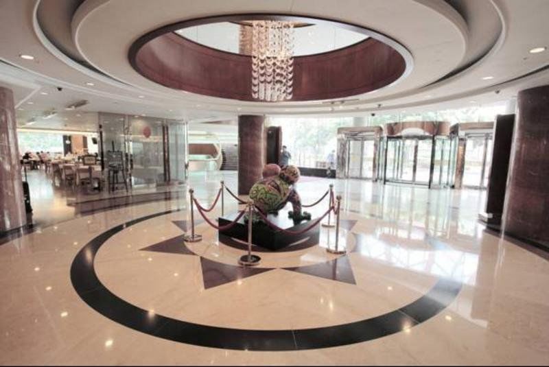 Evergreen Laurel Hotel - טאיצ'ונג מראה חיצוני תמונה The photo depicts an elegant indoor space, likely the lobby of a hotel or a building. The flooring is made of polished marble tiles, featuring a circular design with contrasting black and light-colored sections. At the center, there is a sculpture su