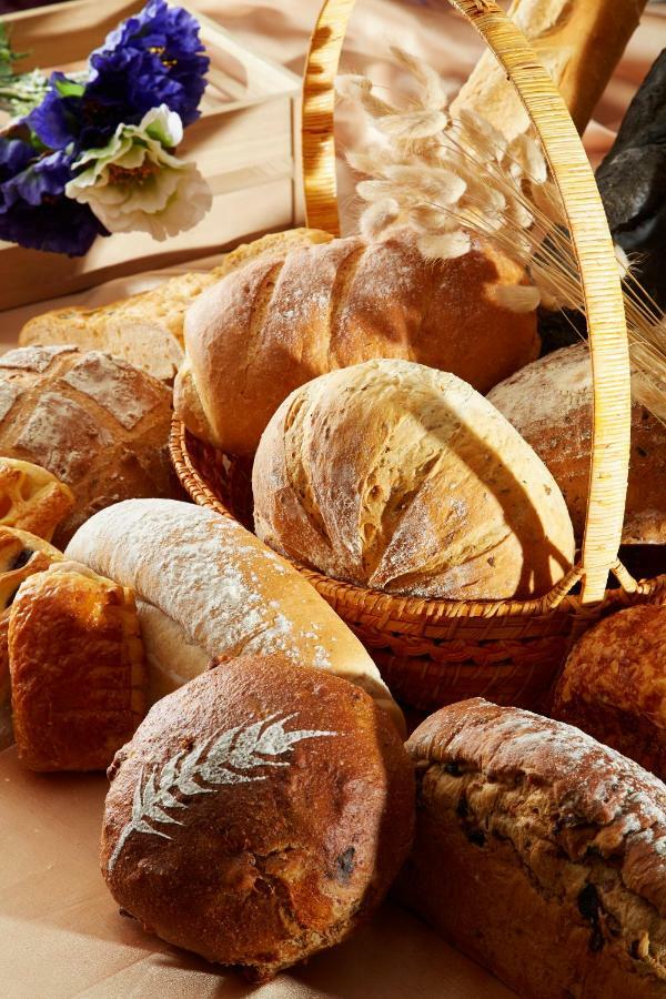 Evergreen Laurel Hotel - טאיצ'ונג מראה חיצוני תמונה The photo shows a variety of freshly baked bread arranged in a woven basket. There are different types of bread, including round loaves, baguettes, and crusty rolls, showcasing a range of colors and textures. Some loaves have distinctive patterns or 