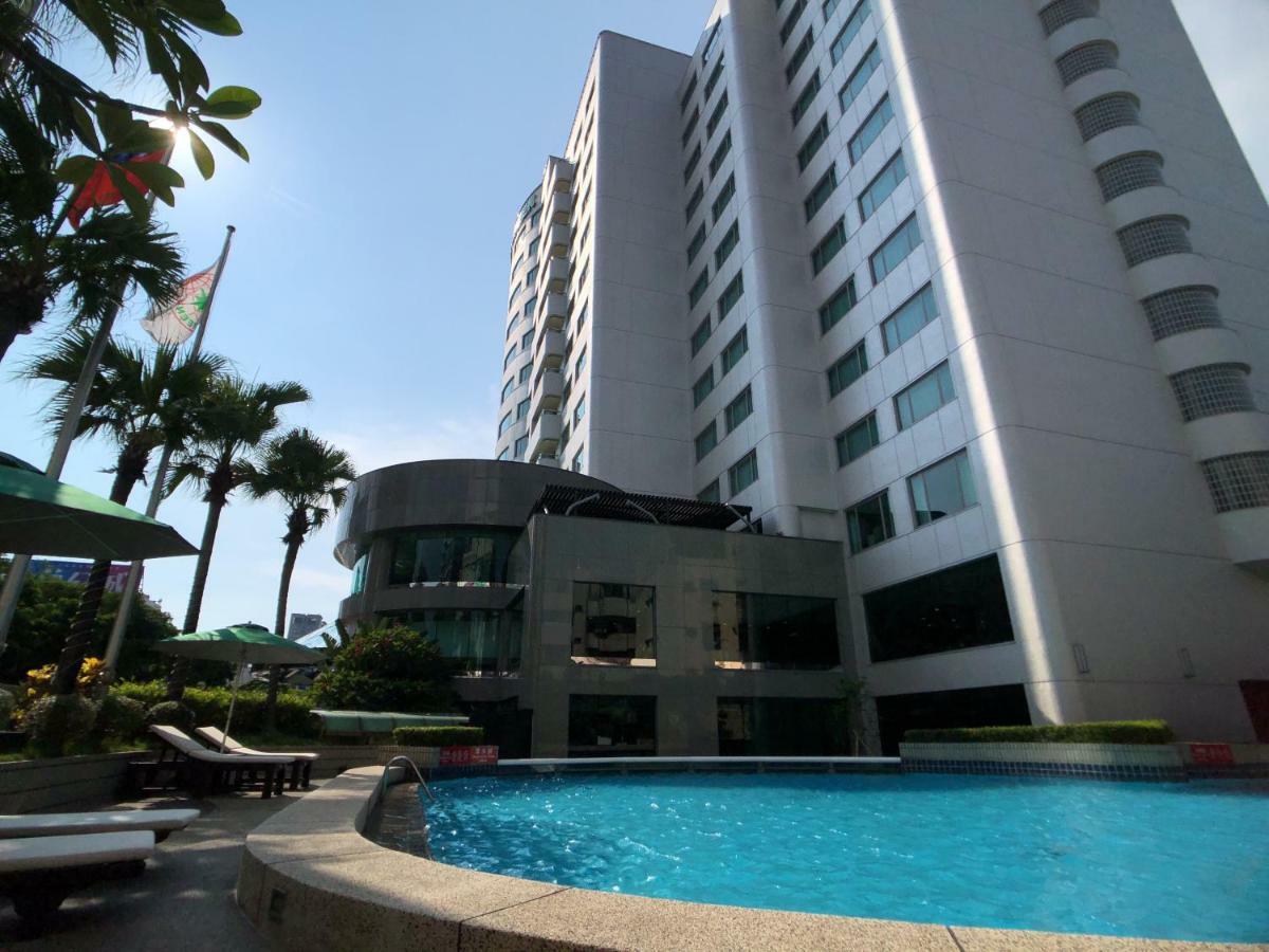 Evergreen Laurel Hotel - טאיצ'ונג מראה חיצוני תמונה The photo depicts a hotel or residential building alongside a swimming pool. The pool is situated in the foreground, with a curved section of the building visible behind it. Surrounding the pool, there are lounge chairs for relaxation. In the backgro