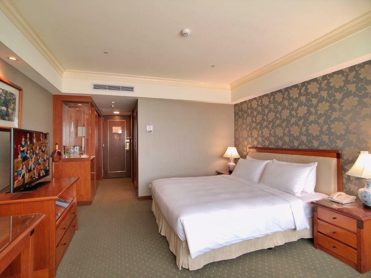 Evergreen Laurel Hotel - טאיצ'ונג מראה חיצוני תמונה The photo shows a well-furnished hotel room. It features a large bed with white linens positioned against a decorative wall. On either side of the bed are bedside tables with lamps. There’s a television mounted on a wooden cabinet across from the bed