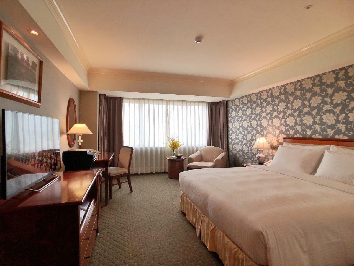 Evergreen Laurel Hotel - טאיצ'ונג מראה חיצוני תמונה The photo shows a hotel room with a spacious layout. It features a large bed with white bedding, bedside lamps, and a decorative headboard. There is a comfortable seating area with an armchair and small table. A desk is present, complete with a lamp 